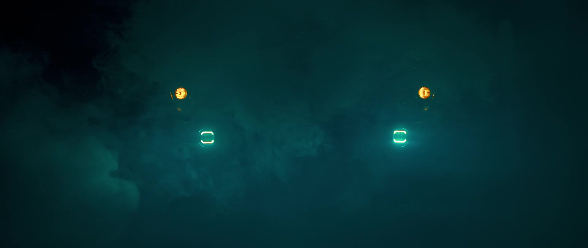 TRAX expedition vehicle concealed in deep blue fog, with bright headlights